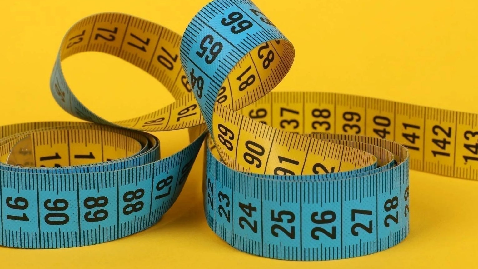 Measuring tape on a yellow background with text about converting between inches and metric.